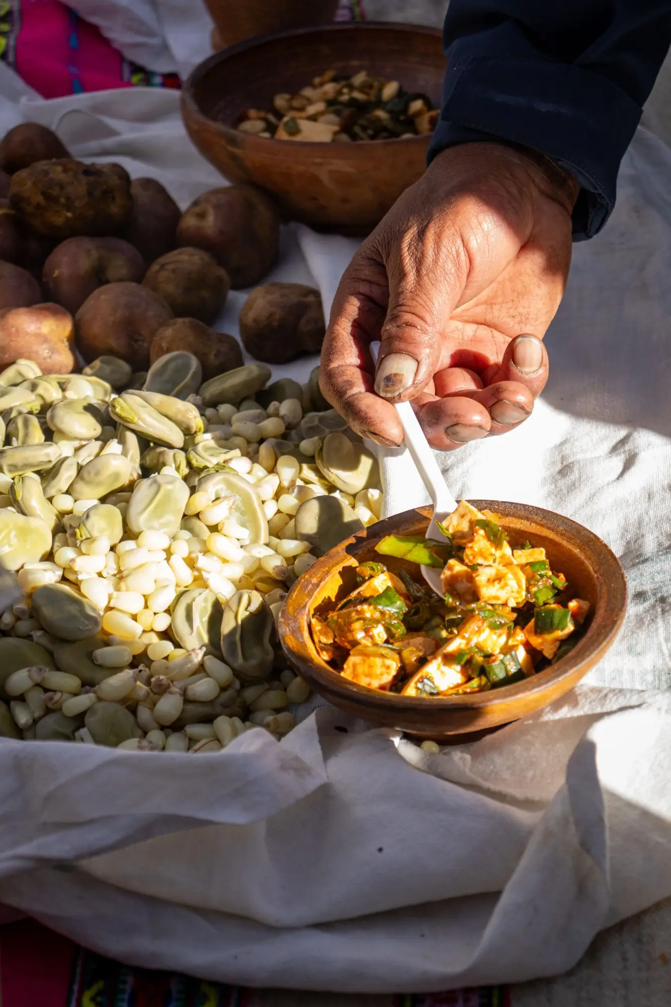 Mano sirviendo queso fresco con ají y cebolla junto a habas, maíz y papas nativas, gastronomía andina de Pomabamba, Ayacucho